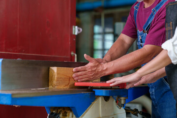 Tutor With Male Carpentry Student In Workshop Studying For Apprenticeship At College Using Bench Saw