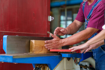 Tutor With Male Carpentry Student In Workshop Studying For Apprenticeship At College Using Bench Saw