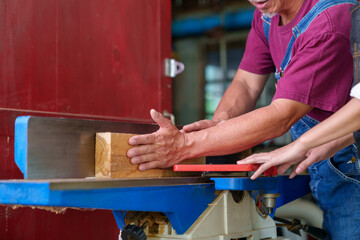 Tutor With Male Carpentry Student In Workshop Studying For Apprenticeship At College Using Bench Saw