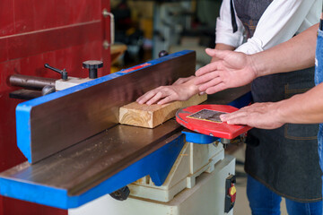 Tutor With Male Carpentry Student In Workshop Studying For Apprenticeship At College Using Bench Saw