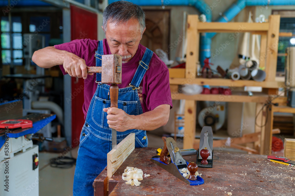 Wall mural carpenter hands working with a chisel and hammer on wooden workbench