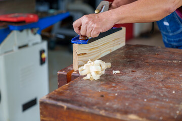 carpenter working with plane on wooden background