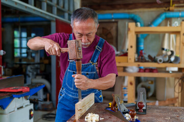 carpenter hands working with a chisel and hammer on wooden workbench