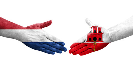 Handshake between Gibraltar and Netherlands flags painted on hands, isolated transparent image.