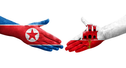 Handshake between Gibraltar and North Korea flags painted on hands, isolated transparent image.