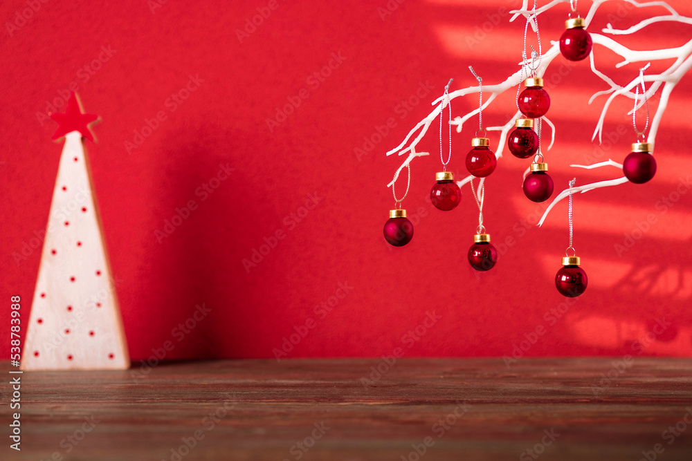 Poster merry christmas with xmas tree and bauble ball at vivid red wall at wooden table.copy space for addi