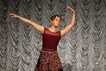 Fototapeta na wymiar Girl dancing on stage. Ballerina performs. Dance lesson in hall.