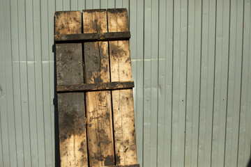 Pallet of wood stands against wall. Details of industrial area. Dirty pallet.