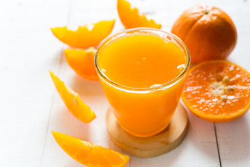 Fresh orange juice in the glass with orange fruit on white wood