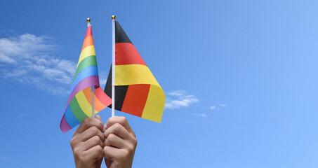 Rainbow flag and Germany national flag holding in hand, soft and selective focus, concept for...