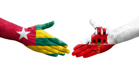 Handshake between Gibraltar and Togo flags painted on hands, isolated transparent image.