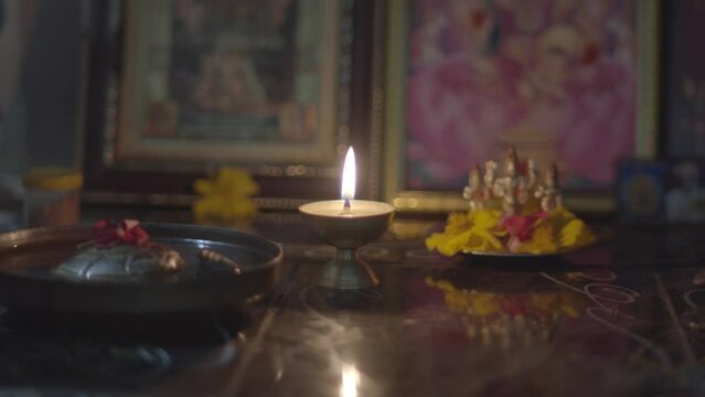 Diwali concept. Home altar with offerings and lit candle. Gimbal, shallow focus