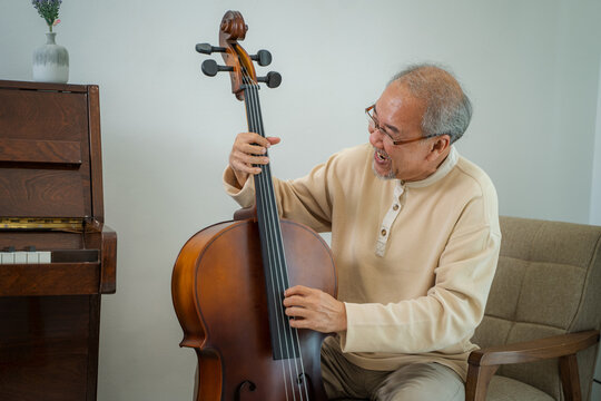 Happy Senior Man Are Playing Double Bass At Home.