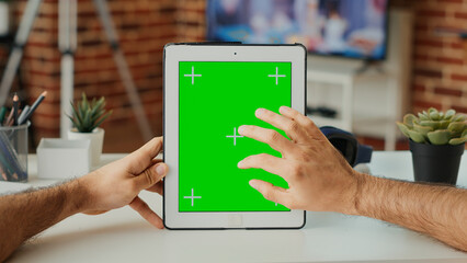 Office employee using digital gadget with greenscreen template, vertically holding portable tablet...