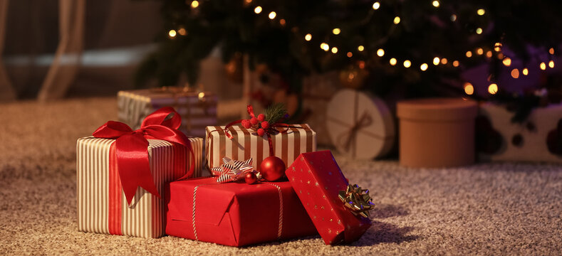 Beautiful Christmas gifts on floor near fir tree in room