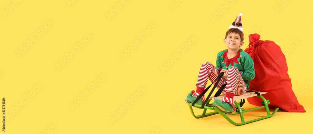 Sticker cute little elf with santa bag sitting on sledge against yellow background with space for text