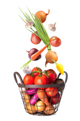 Many healthy vegetables falling into basket on white background