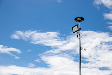 Fototapeta na wymiar Public city light with solar panel powered on blue sky with clouds