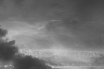 gray monochrome cloudy sky background with plain trail between clouds
