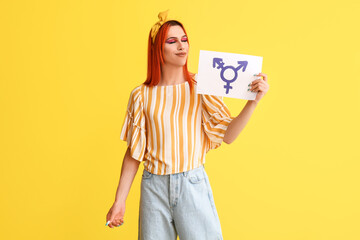Stylish transgender woman holding paper sheet with transgender symbol against yellow background - obrazy, fototapety, plakaty