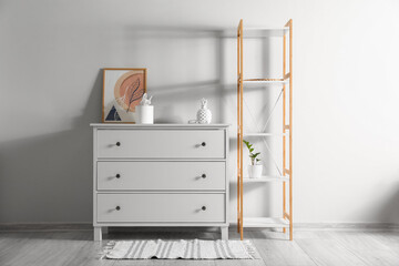 Fototapeta na wymiar Chest of drawers with decor and shelving unit near light wall