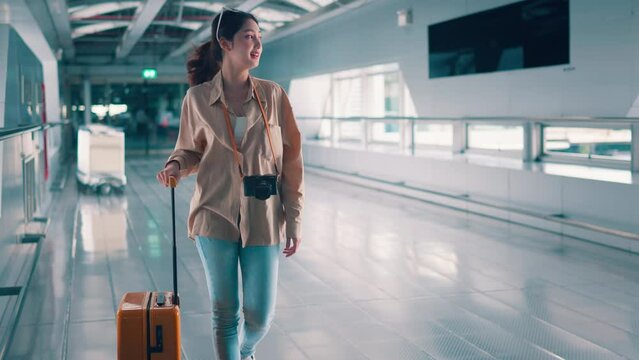 Happiness smiling asian woman passenger walking with a yellow suitcase luggage at airport terminal, Woman on way to flight boarding gate, Tourist journey trip concept