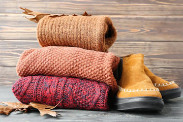 Stack of children's sweaters and shoes on wooden background