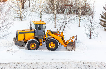 Snow clearing. Tractor clears the way after heavy snowfall. A large orange tractor removes snow...