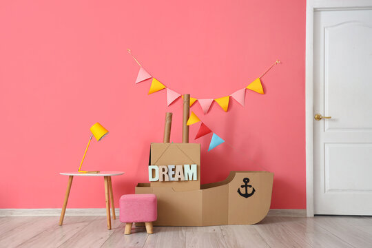 Toy cardboard ship and table with lamp in children's room