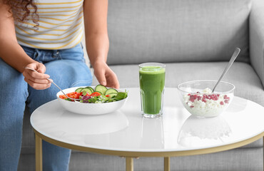 Young African-American woman eating healthy food at home. Diet concept