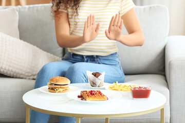 Young African-American woman refusing from junk food at home. Diet concept