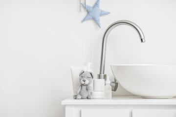 Modern sink, cute toy and bath accessories for children near white wall