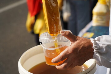 The seller pours fresh honey into a container at the market.