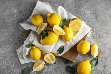 Wooden board with fresh ripe lemons on grunge background