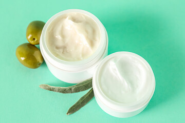 Jars of natural olive cream on color background, closeup