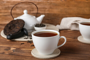 Fototapeta na wymiar Cup of puer tea on wooden background, closeup