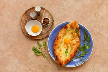 Plate with tasty Ajarian khachapuri, arugula and spices on color background