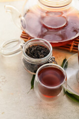 Cup of aromatic black tea on light background