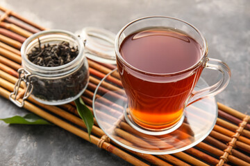 Bamboo mat with cup of black tea on grunge background, closeup