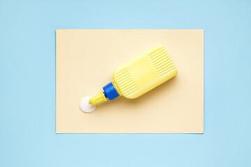 Bottle of glue with paper sheet on blue background
