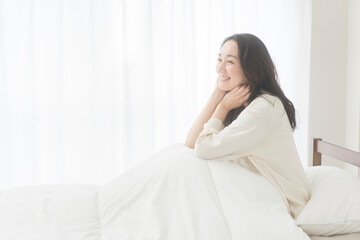 朝、ベッドでリラックスしている女性	