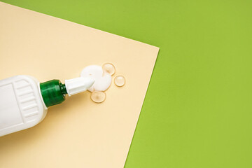 Bottle of glue with paper sheet on green background, closeup