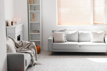 Interior of light living room with grey sofas, shelving unit and fireplace