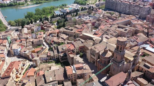 Scenic aerial view of medieval Roman Catholic Cathedral of Saint Mary surrounded by residential buildings with terracotta tiled roofs in historical center of Tudela on sunny spring day, Spain. High