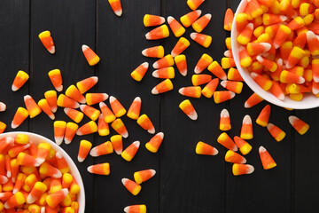 Bowls with Halloween candy corns on black wooden background