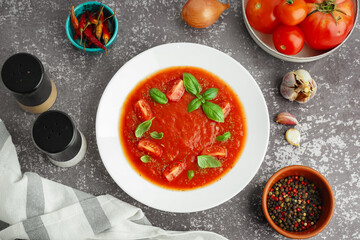 Plate with tasty tomato soup and spices on grunge background