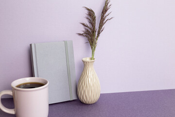 Purple notebook and cup of coffee, plant on desk. workspace