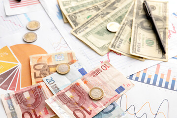 Different banknotes with coins on diagrams, closeup. Exchange rate concept