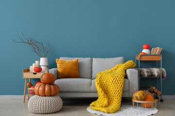 Interior of cozy living room with pumpkins, sofa and pouf