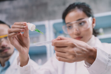 Two researcher are drop and looking at liquid to plate in their hands at laboratory.